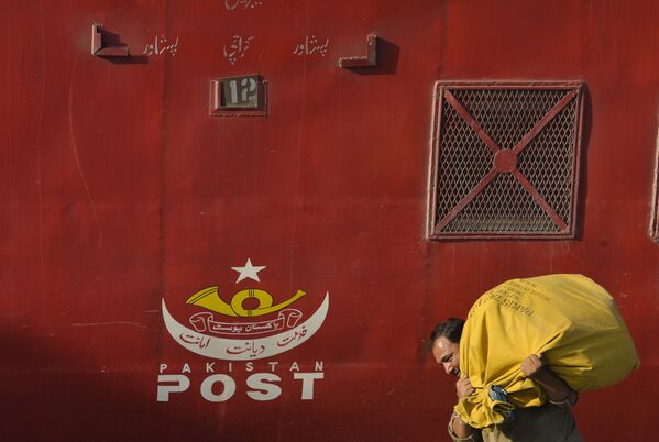 Carteiro paquistanês carrega sacola com cartas em estação de trem em Lahore, no Paquistão   - Sputnik Brasil