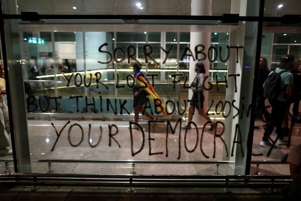 Pessoas passam por um graffiti no aeroporto de Barcelona, após o veredicto em um julgamento em torno do proibido referendo da independência - Sputnik Brasil