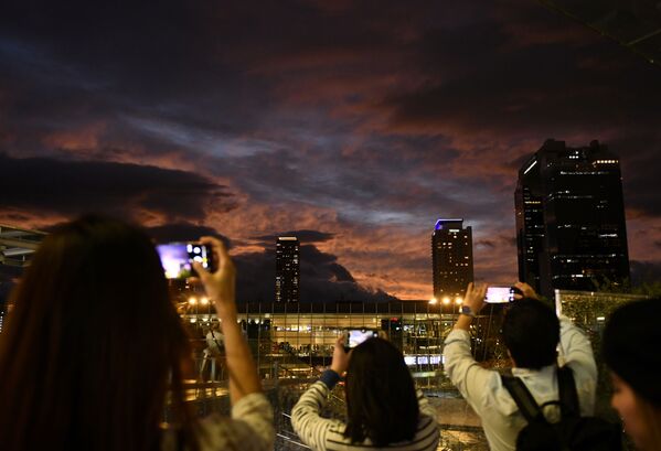 Pessoas tiram fotos do céu durante o pôr do sol durante a aproximação do tufão Hagibis da cidade de Osaka, Japão - Sputnik Brasil