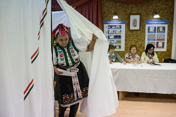 Mulher em roupa tradicional sai da cabine de votação durante eleições locais no povoado de Rimoc, Hungria - Sputnik Brasil