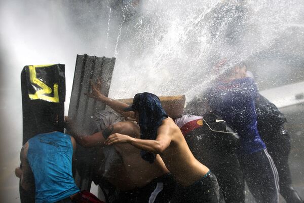Manifestantes tentam se proteger de jatos de água jogados pela tropa de choque para dispersar manifestantes - Sputnik Brasil