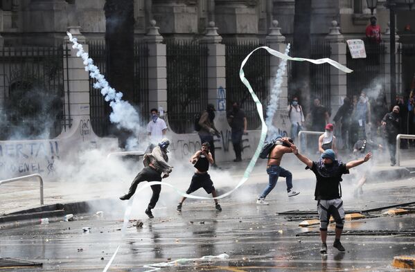 Manifestantes são atingidos por bombas de gás lacrimogêneo durante protestos e depredações no Chile - Sputnik Brasil