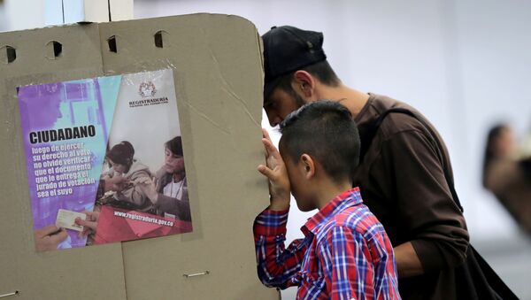 Um homem acompanhado por seu filho deposita seu voto em Bogotá nas eleições locais da Colômbia, em 27 de outubro de 2019. - Sputnik Brasil