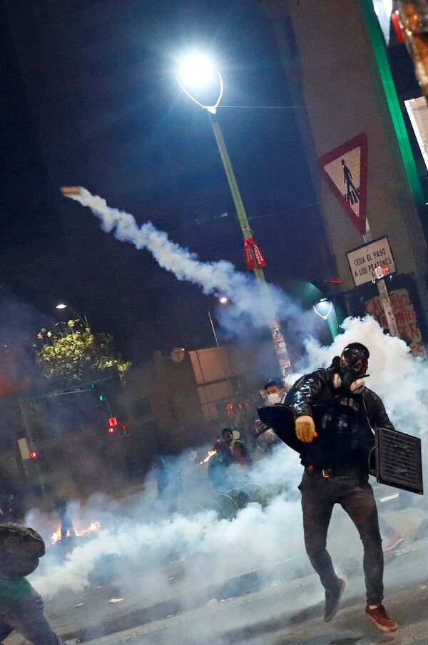 Manifestante, protegido com máscara de gás, atira bomba de gás lacrimogênio durante protestos em La Paz, ocorridos no dia 31 de outubro de 2019 - Sputnik Brasil