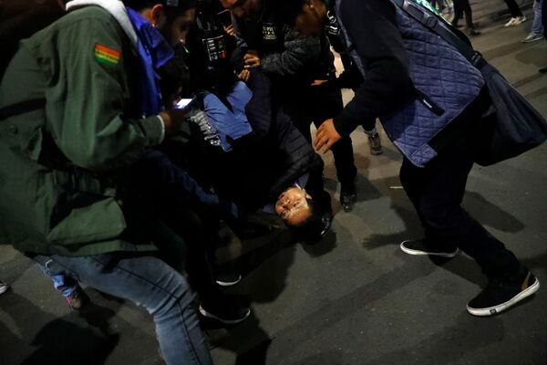 Grupo acode uma mulher durante confronto entre manifestantes que eclodiu na cidade boliviana de La Paz, nesta terça-feira (5). - Sputnik Brasil