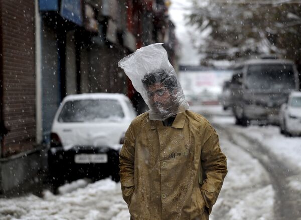 Homem cobre a cabeça com um saco plástico enquanto cai neve em Srinagar, na Caxemira controlada pela Índia - Sputnik Brasil