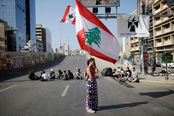  Mulher com a bandeira do Líbano participa de um bloqueio de rodovia no país árabe durante manifestações contra o governo em Beirute - Sputnik Brasil