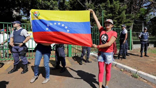 Apoiantes do presidente da Venezuela, Nicolás Maduro, seguram bandeira diante da embaixada da Venezuela em Brasília, Brasil, 13 de novembro de 2019 - Sputnik Brasil
