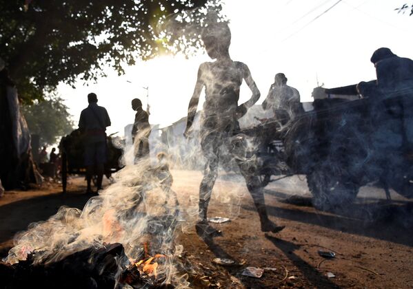 Pessoas passam em frente a um monte de lixo em chamas na cidade indiana de Calcutá - Sputnik Brasil