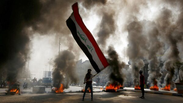 Manifestante com a bandeira do Iraque durante ação de protesto na cidade de Najaf, Iraque - Sputnik Brasil