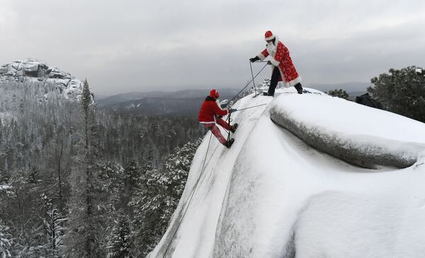 Dois homens de uma organização de busca e salvamento, um vestido de Papai Noel russo e outro de Santa Claus treinam escalada de rochedo na região russa de Krasnoyarsk - Sputnik Brasil