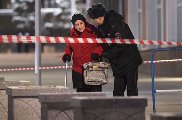 Um policial ajuda uma mulher a passar em uma zona do cordão de isolamento do prédio da FSB no centro da capital russa  - Sputnik Brasil