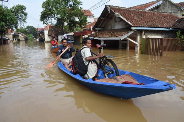 Pessoas passando de barco por uma estrada inundada na Indonésia
 - Sputnik Brasil