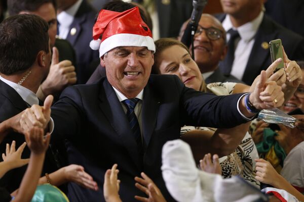 Presidente Jair Bolsonaro usando chapéu de Papai Noel durante a celebração do Natal com os funcionários e estudantes no Palácio do Planalto, em Brasília
 - Sputnik Brasil