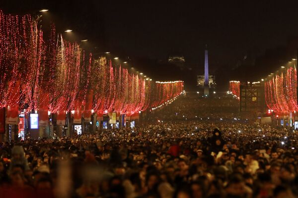 Pessoas em Paris assistindo a queima de fogos sobre o Arco do Triunfo - Sputnik Brasil