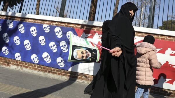 Mulher iraniana caminha com retrato do general Qassem Soleimani perto de muro com representação de bandeira dos Estados Unidos - Sputnik Brasil