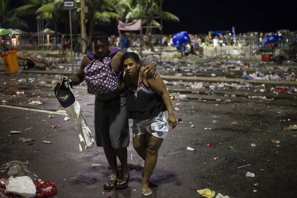 Mulher recebe ajuda após confrontos entre policiais e foliões após o início oficial do carnaval na praia de Copacabana, no Rio de Janeiro - Sputnik Brasil