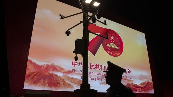 Agente de segurança passa por câmeras de vigilância em Pequim, perto de tela expondo o 70º aniversário de fundação da República Popular da China - Sputnik Brasil