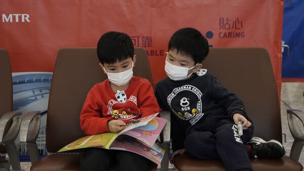 Crianças leem revista utilizando máscaras em estação de trem em Hong Kong. - Sputnik Brasil