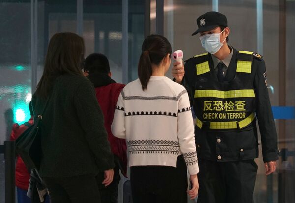 Passageiras passam por controle térmico no Aeroporto Internacional Tianhe, em Wuhan, China - Sputnik Brasil