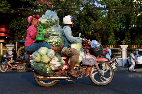 Mulher transporta vegetais empilhados em moto no Camboja
 - Sputnik Brasil