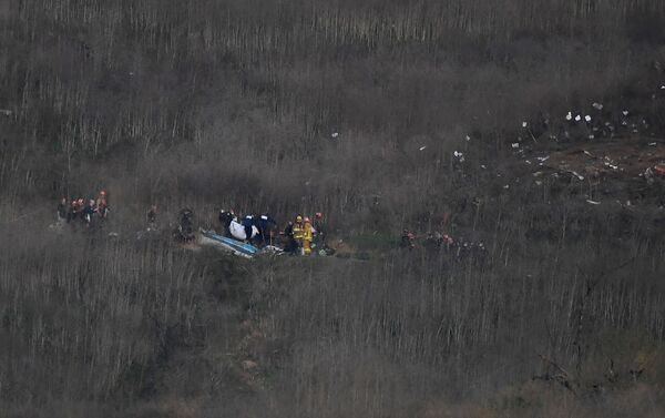 Membros do corpo de bombeiros e legistas trabalham próximos aos destroços do helicóptero que levava Kobe Bryant e mais 8 passageiros, que caiu em Calabasas, na Califórnia - Sputnik Brasil