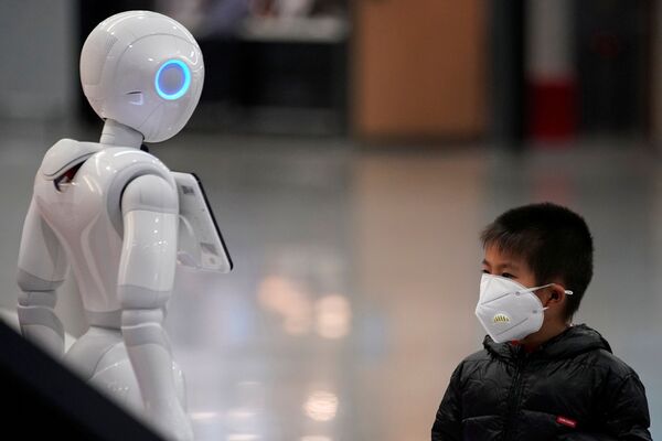Garoto usa máscara e observa robô no aeroporto internacional de Xangai, na China, em 27 de janeiro de 2020 - Sputnik Brasil