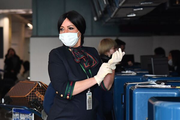 Funcionária de aeroporto usa luvas e máscara de proteção para checar passageiros provenientes da China, no Aeroporto Internacional de Roma, na Itália, em 23 de janeiro - Sputnik Brasil
