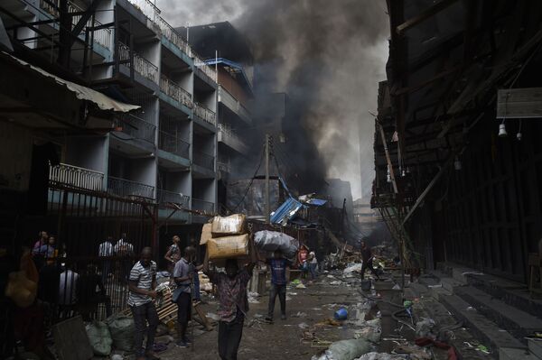 Populares carregam mercadorias que restaram de um incêndio que acometeu parte do mercado de Balogun, na Nigéria - Sputnik Brasil