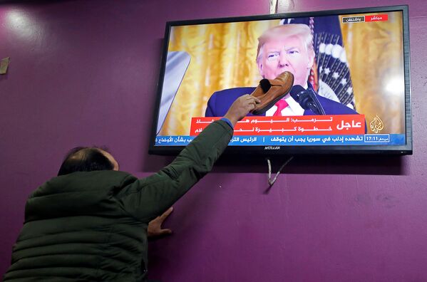 Palestino põe sapato em uma tela de televisão enquanto o presidente americano, Donald Trump, anuncia seu plano de paz para o conflito israelense-palestino em uma cafeteria em Hebron, na Cisjordânia ocupada por Israel - Sputnik Brasil