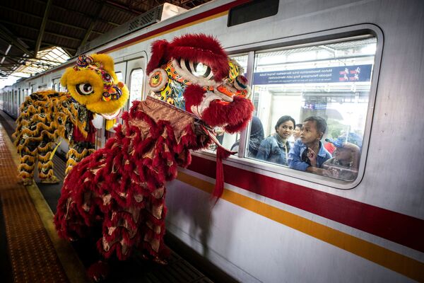 Passageiros observam foliões com fantasias de leão durante o Ano Novo lunar chinês em Jacarta, Indonésia - Sputnik Brasil