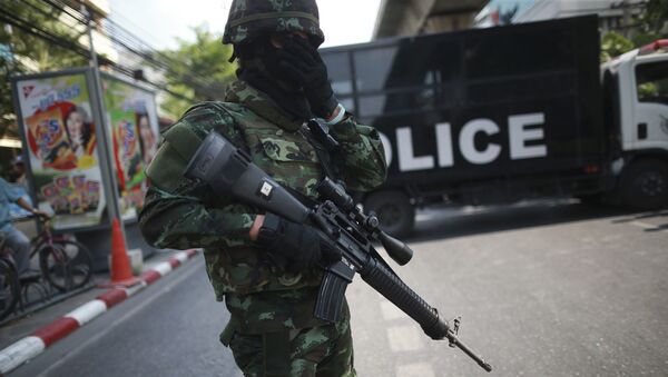 Um policial armado em frente a um caminhão da polícia na Tailândia. - Sputnik Brasil