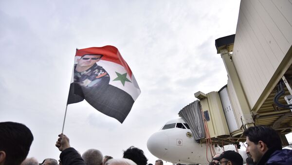 Homem levanta bandeira da Síria com imagem de Bashar Assad - Sputnik Brasil