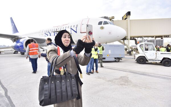 Mulher tirando foto no aeroporto de Damasco em dia do 1º voo de Damasco para Aleppo em 8 anos - Sputnik Brasil