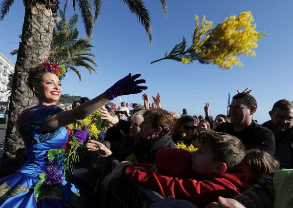 Artista lança flores a populares durante a parada de flores na 136ª Parada de Carnaval em Nice, França - Sputnik Brasil