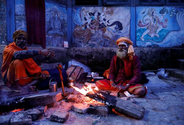 Religiosos hindus sadhus sentam ao lado de fogueira no templo de Pashupatinath, no Nepal - Sputnik Brasil