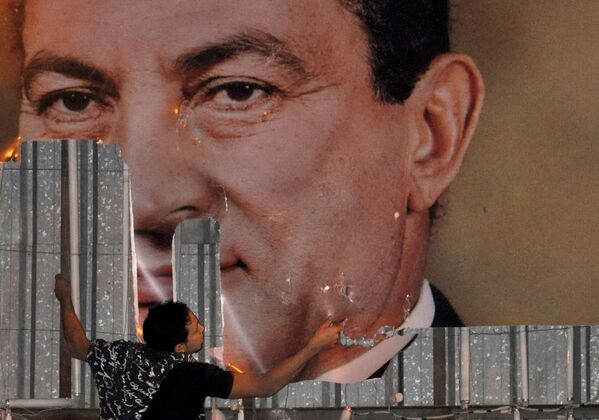 Opositor de Mubarak esconde painel com sua foto, em meio a protestos na cidade de Alexandria, em 2011. - Sputnik Brasil