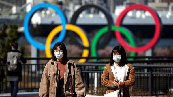 Pedestres utilizam máscara protetora próximo ao símbolo das Olimpíadas de Verão de Tóquio, programadas para serem iniciadas em julho de 2020 - Sputnik Brasil