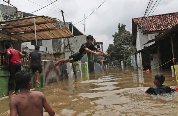 Crianças brincando em área alagada na capital indonésia, Jacarta, após chuvas noturnas - Sputnik Brasil