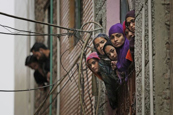 Muçulmanas indianas olham pela janela em uma rua de Nova Deli enquanto agentes de segurança do país passam pelo local - Sputnik Brasil