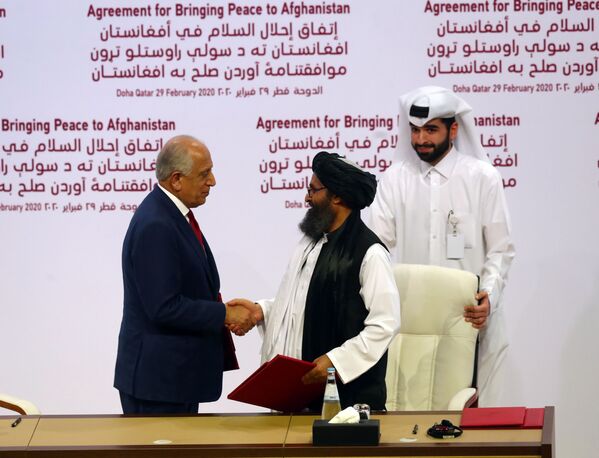 Representante dos EUA para o Afeganistão, Zalmay Khalizad (à esquerda) aperta mão do representante do Talibã (Abdul Ghani Baradar) em ato de assinatura de acordo de paz entre ambos os lados em 29 de fevereiro no Qatar - Sputnik Brasil