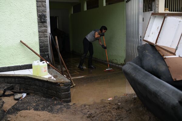 Mulher tira água suja de garagem de casa no bairro carioca de Realengo, na Zona Norte da cidade após fortes chuvas - Sputnik Brasil