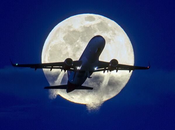 Avião sobrevoando o aeroporto alemão de Frankfurt, tendo ao fundo uma lua cheia - Sputnik Brasil
