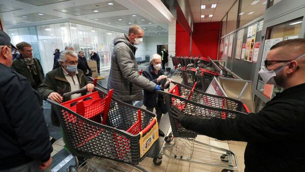 Guarda controla a entrada de um supermercado em Bruxelas, na Bélgica, que abre uma hora antes apenas para pessoas acima de 65 anos, em uma tentativa de proteger os mais vulneráveis contra os riscos de contágio do coronavírus, 18 de março de 2020 - Sputnik Brasil