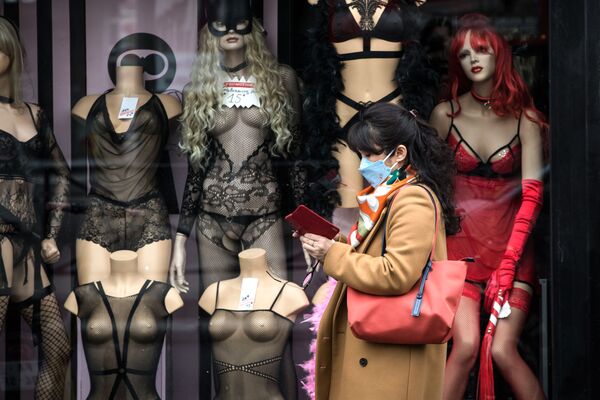 Mulher usando máscara passa ao lado de vitrine de loja de materiais adultos em Pigalle, Paris - Sputnik Brasil