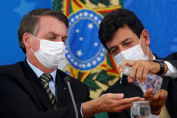 Presidente brasileiro, Jair Bolsonaro, em conferência junto com seu ministro da Saúde, Luiz Henrique Mandetta, passa álcool-gel na mão e usa máscara - Sputnik Brasil