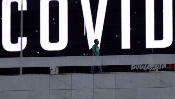 Homem passa por tela LED ao ar livre durante pandemia de coronavírus em Brasília, Brasil, 24 de março de 2020 - Sputnik Brasil