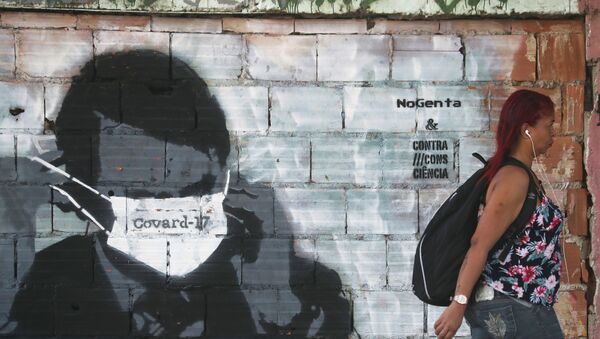 Pedestre passa por muro grafitado no Rio de Janeiro, em 26 de março de 2020 - Sputnik Brasil