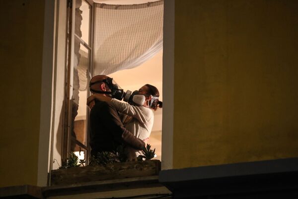 Homem e mulher com máscaras de proteção se abraçam em janela na cidade francesa de Nice, em 24 de março de 2020 - Sputnik Brasil