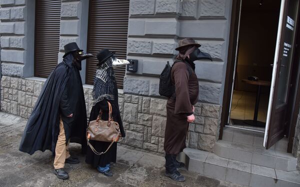 Pessoas fantasiadas caminham em rua durante pandemia de coronavírus, em Lvov, Ucrânia - Sputnik Brasil